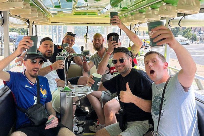 A group of people on a bus, some holding cups, with a table in the center. 5