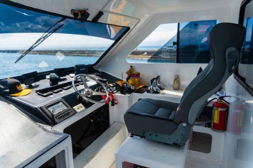 Interior de un barco con timón, tablero de control y zona de estar. 1