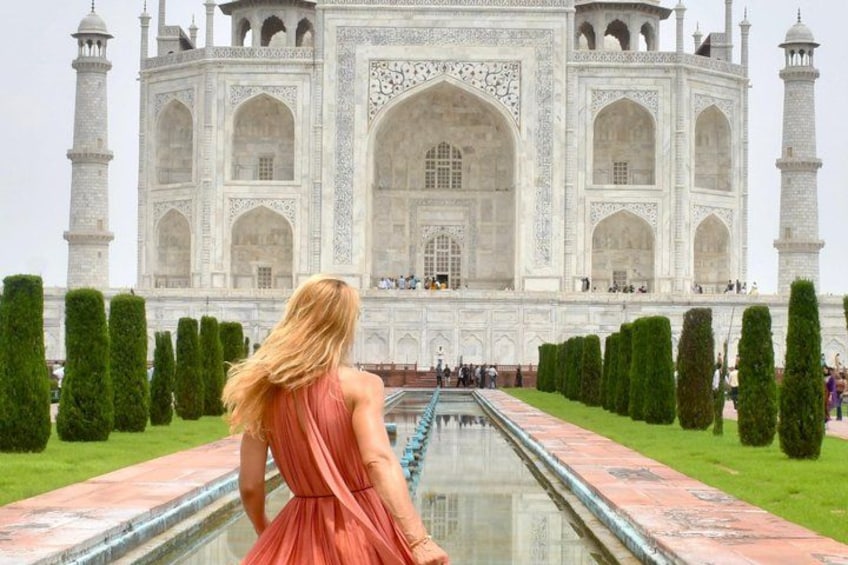 Il Taj Mahal con una persona in abito rosa che vi si trova di fronte. 3