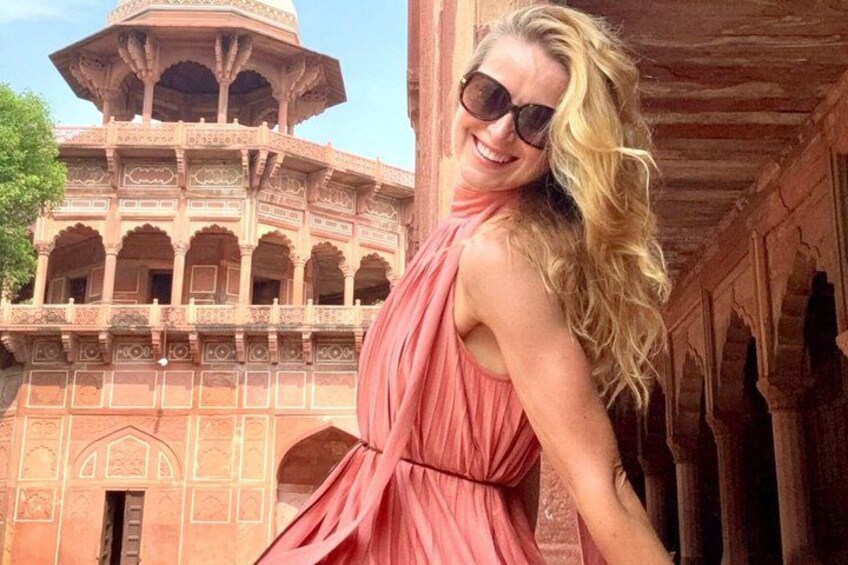 Una donna con un abito rosa in piedi di fronte a un edificio storico con archi e decorazioni elaborate. 5