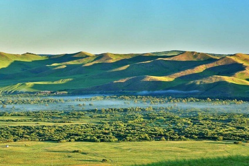 Rolling hills, a lake, and a distant building. 4