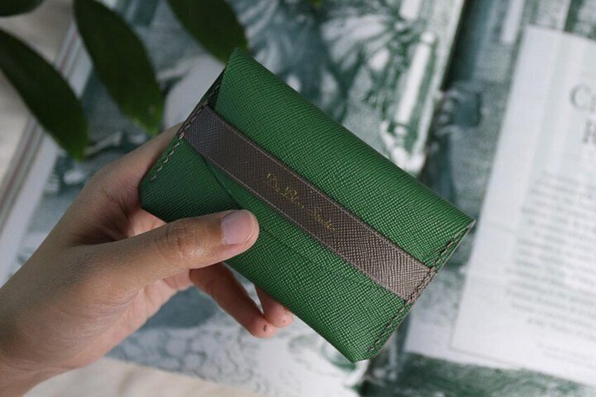 Una mano sosteniendo una cartera verde con una correa marrón. 4