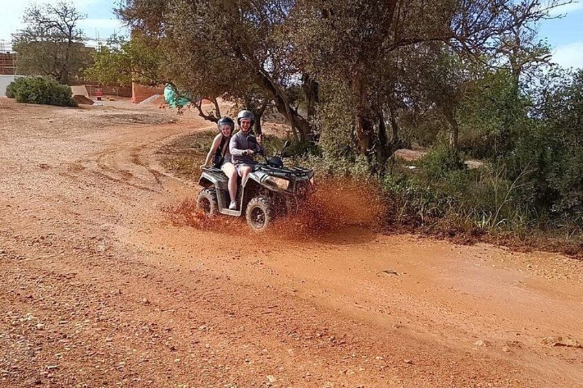 A dirt road with an ATV and two people riding it. 3
