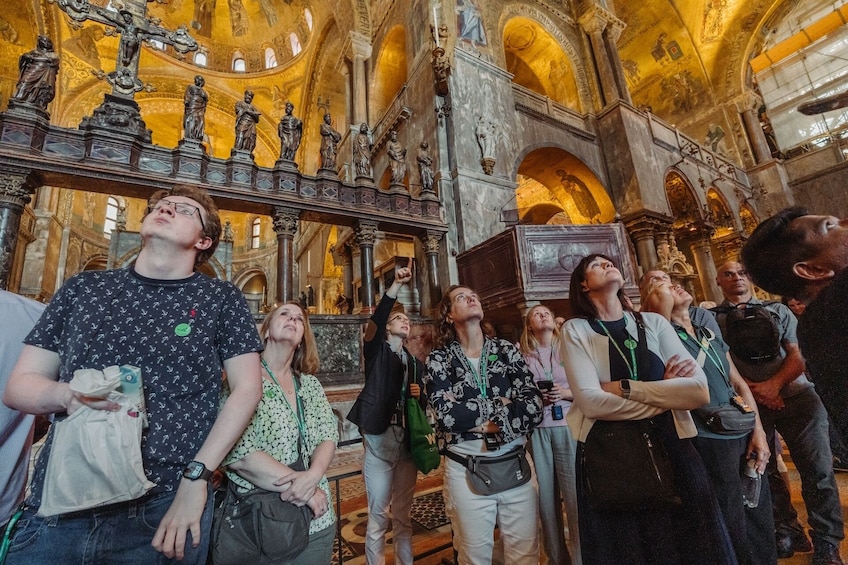 En gruppe mennesker indeni en katedral, der ser op på et stort krucifiks. 4