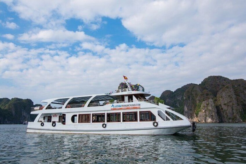 Een witte riviercruiseboot met een glazen dak en een vlag, afgemeerd nabij een rotsachtige kustlijn. 3