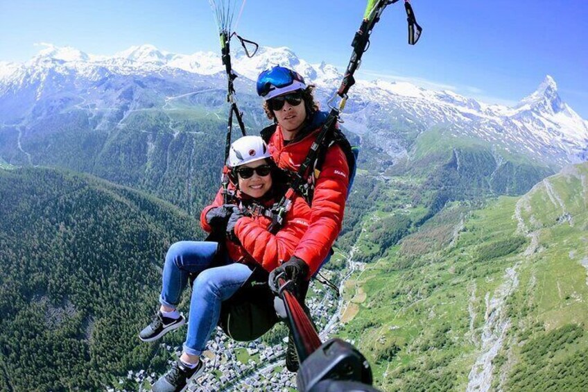Two people in red jackets on a mountain, with a snowy mountain range in the background. 5