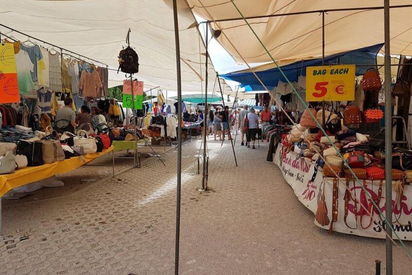 A market with various stalls selling bags and clothing. 2