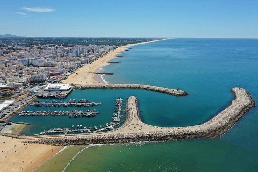 Eine Küstenstadt mit Strand, Hafen und einer geschwungenen Mole. 4