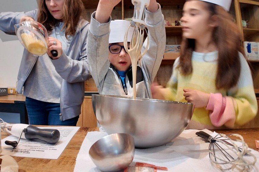 Three people engaged in a cooking activity, using a large mixing bowl and a stand mixer. 2