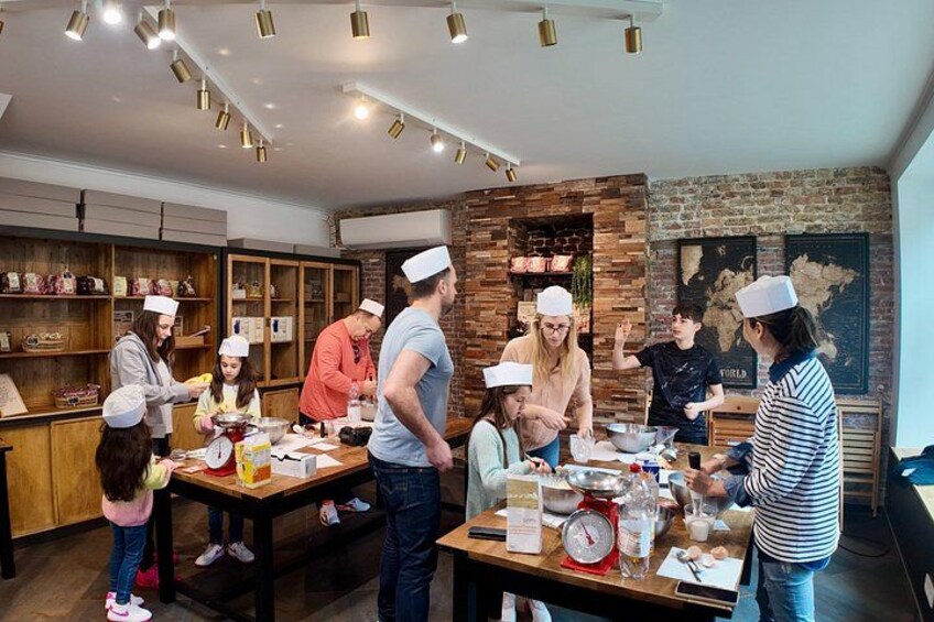 A group of people in a kitchen setting, some wearing chef hats, engaged in cooking activities. 1