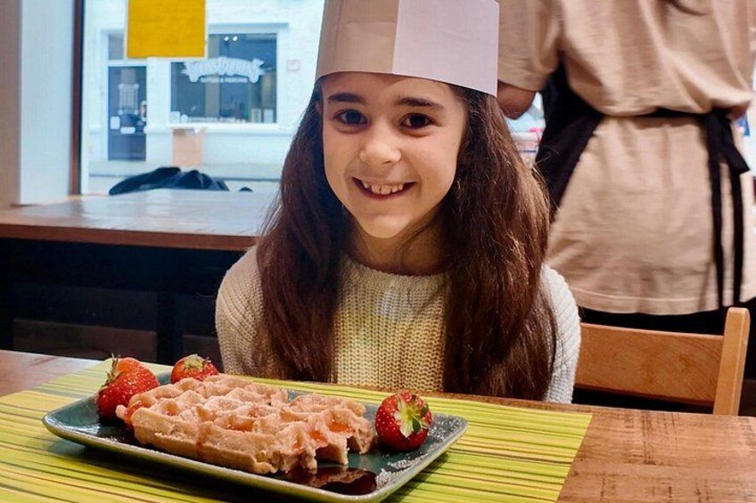 A person sitting at a table with a waffle and strawberries. 3