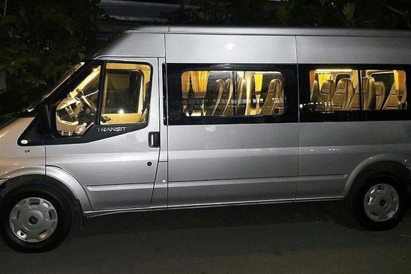 A silver van with 'TRANSIT' written on the side, parked on a street at night. 3