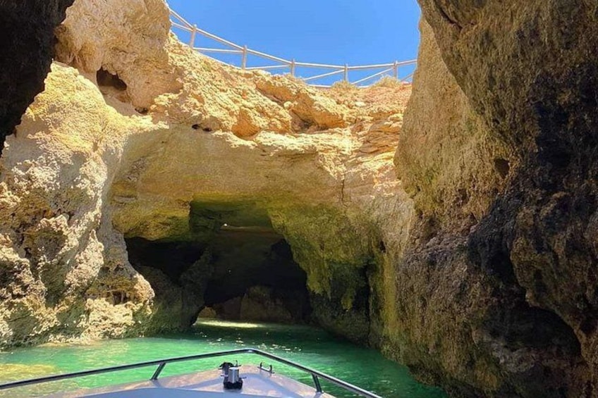Ein Boot fährt durch eine felsige Höhle, darüber eine hölzerne Brücke. 4