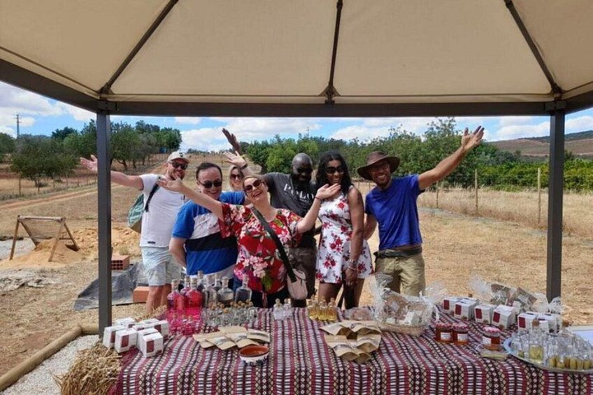 A group of people posing under a canopy with a table of food and drinks. 4
