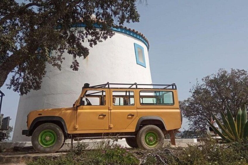 A yellow off-road vehicle parked in front of a white cylindrical building with a blue trim. 3