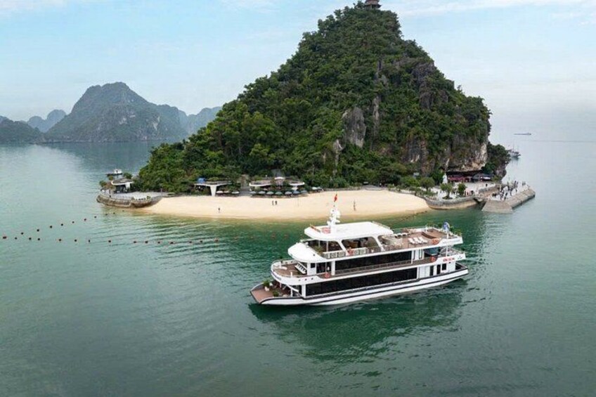 A large boat on calm waters near a small island with a beach and structures. 5