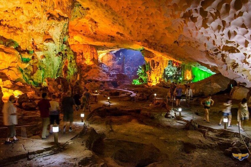 En grotta med upplysta klippformationer och besökare. 2