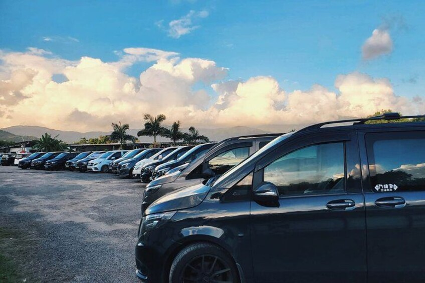 A row of parked cars in a parking lot with a clear sky and mountains in the background. 2