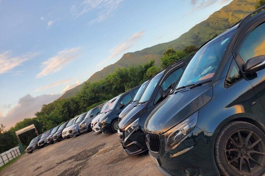 A row of parked cars in a parking lot with mountains in the background. 3