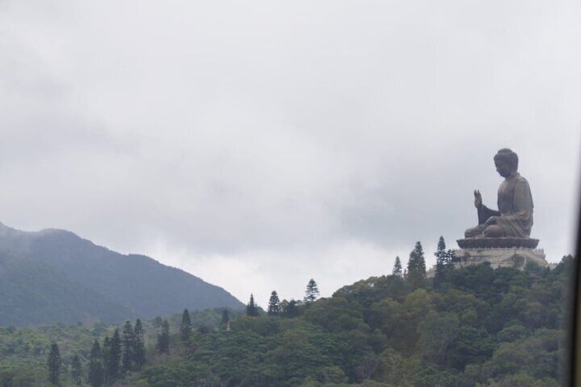 A large seated Buddha statue on a hilltop, surrounded by trees and mountains. 5