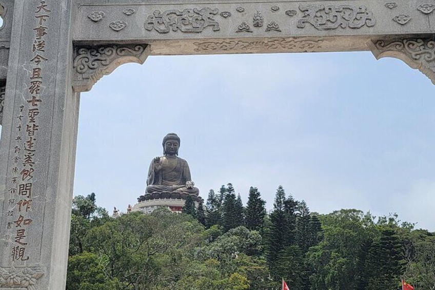 A large Buddha statue under a decorative archway with Chinese inscriptions. 1