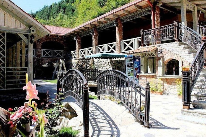 A rustic building with a stone facade, a metal staircase, and a decorative metal fence. 2