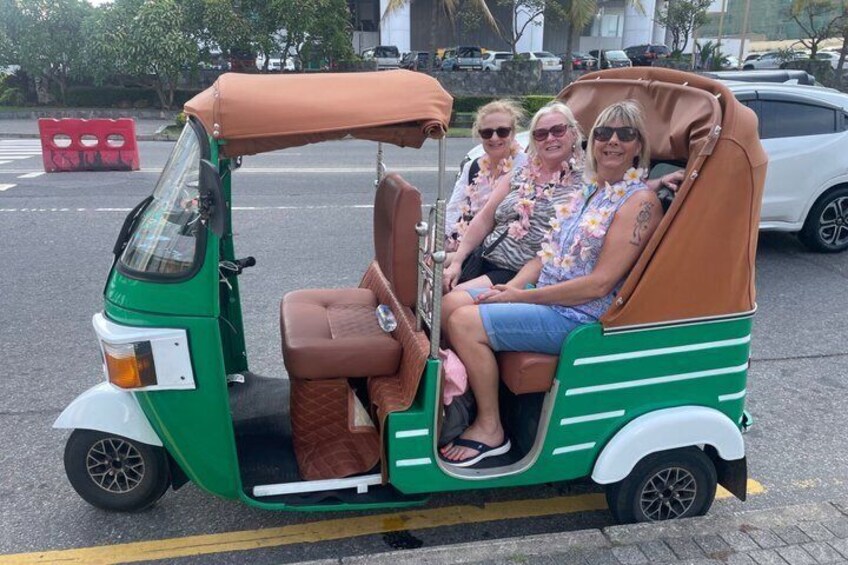 A green and brown three-wheeled vehicle with passengers. 1
