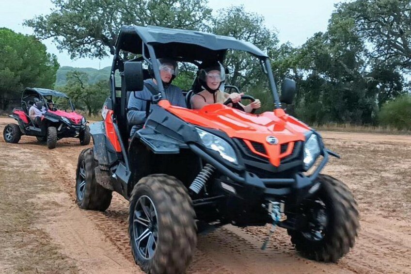 A person driving a red ATV on a dirt path with trees in the background. 1