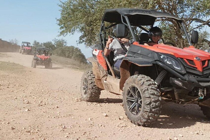 A red ATV on a dirt road with another ATV in the background. 4