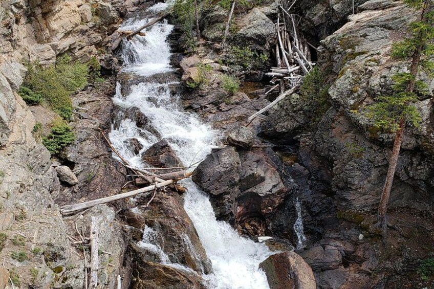 Een rotsachtige waterval met stromend water, omringd door bomen en rotsen. 1