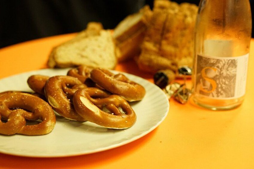 Un piatto di brezel, una bottiglia e del pane su un tavolo. 4