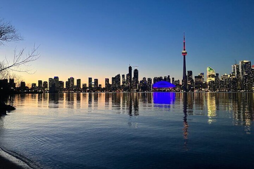 A city skyline at dusk with a prominent tower reflecting on calm water. 3