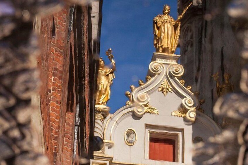 A building with ornate gold decorations and statues on the roof. 2