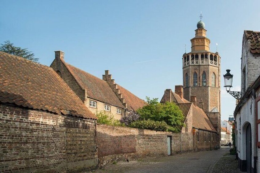 A cobblestone street lined with historic buildings and a prominent tower. 4