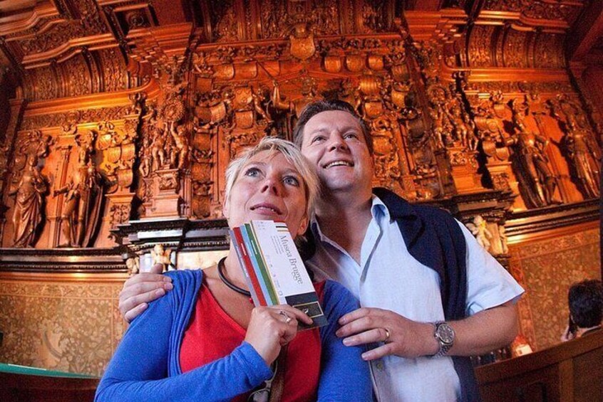 A person holding a book in front of a detailed sculpture. 5