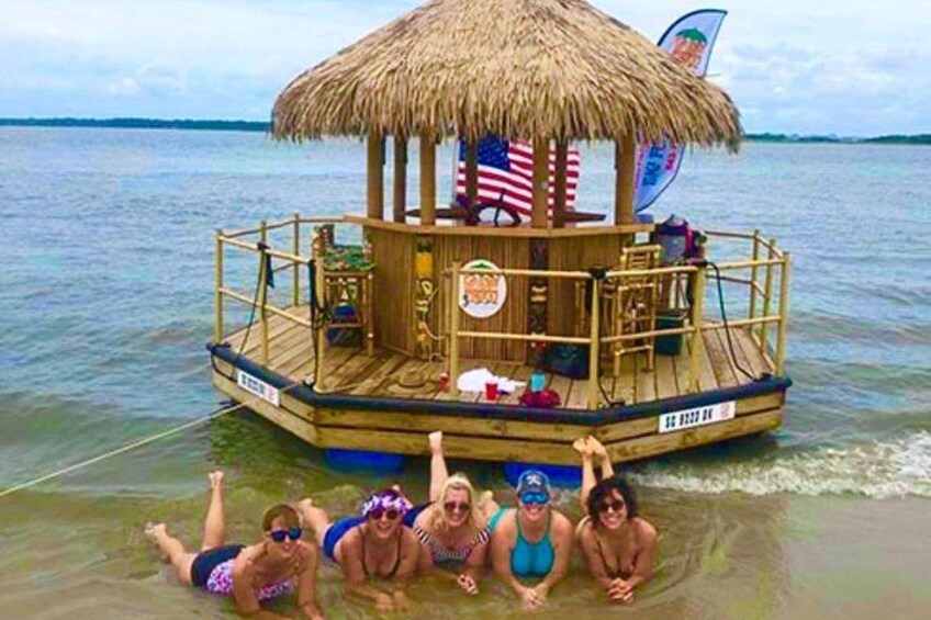 A boat with a thatched roof and American flags, floating on calm water. 5