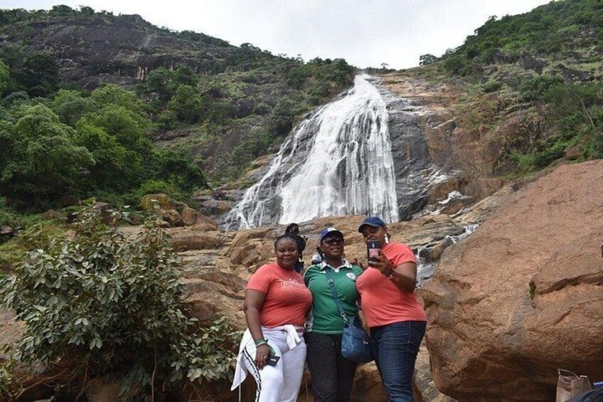 Una cascata, vegetazione lussureggiante e un gruppo di persone che si fanno una foto. 4
