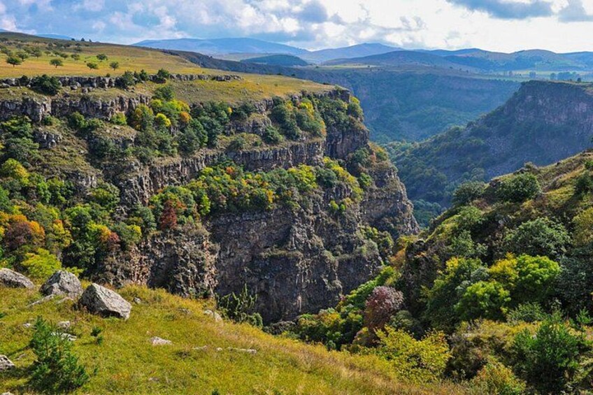A rugged mountain landscape with steep cliffs, dense greenery, and a valley in the background. 2