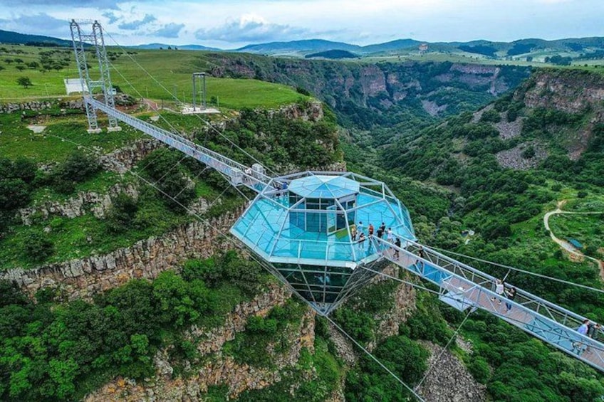 A glass bridge over a canyon with a glasshouse structure at the end. 1