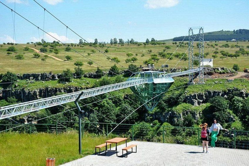 A suspension bridge, a picnic table, and a person standing on a platform. 3