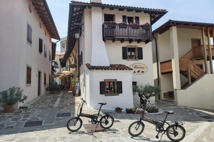 A narrow street with two bicycles parked in front of a building with a balcony. 3