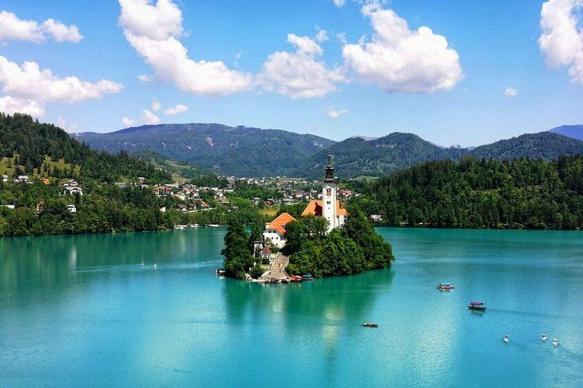A lake with a small island featuring a church, surrounded by mountains and clear skies. 2