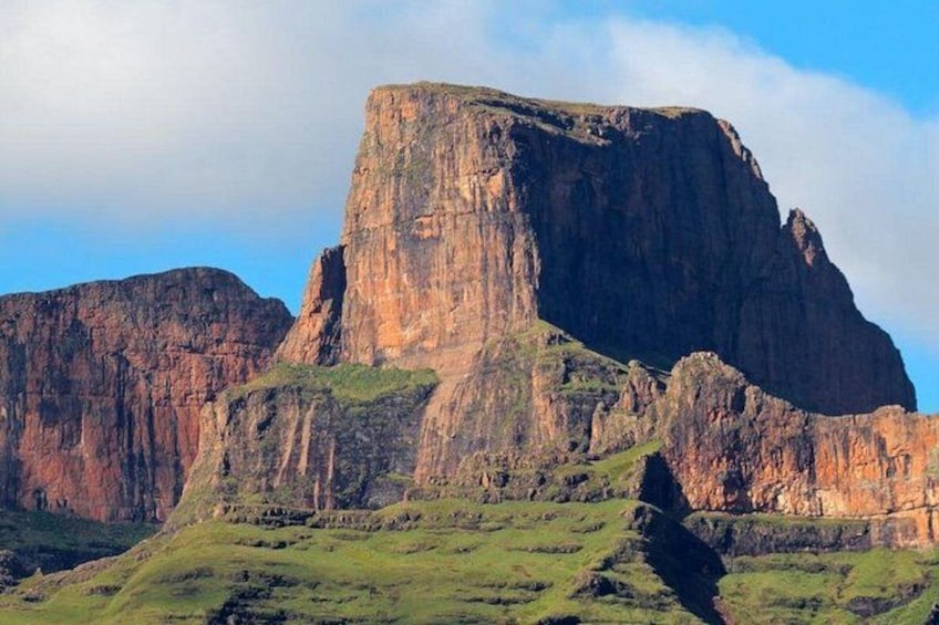 A large rock formation with a flat top and steep sides, surrounded by green hills. 4