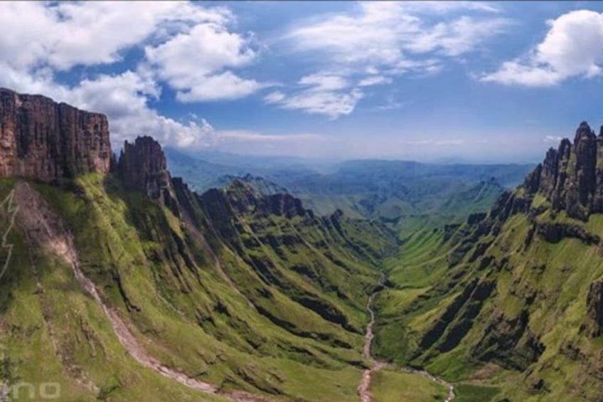 A valley with steep cliffs and a winding path. 5