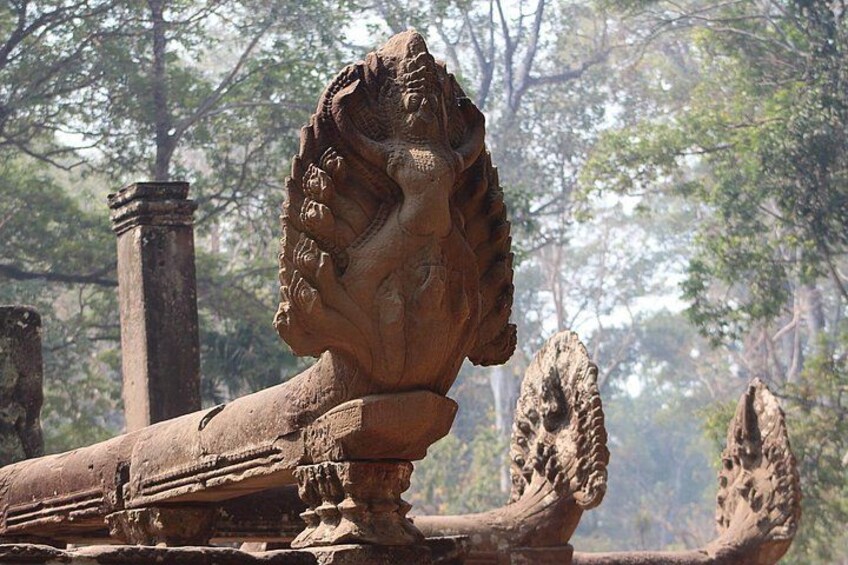 A weathered stone lion statue in a forested area. 4