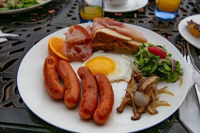 A plate with sausages, a fried egg, bacon, grilled meat, and a salad. 4