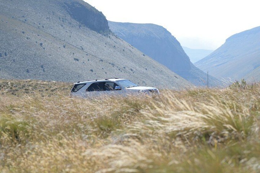 A vehicle in a grassy field with mountains in the background. 5