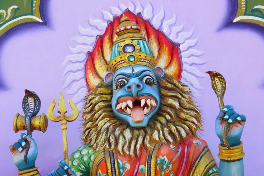 Una colorata statua di una divinità con testa di leone, che regge un tridente e un tamburo. 5