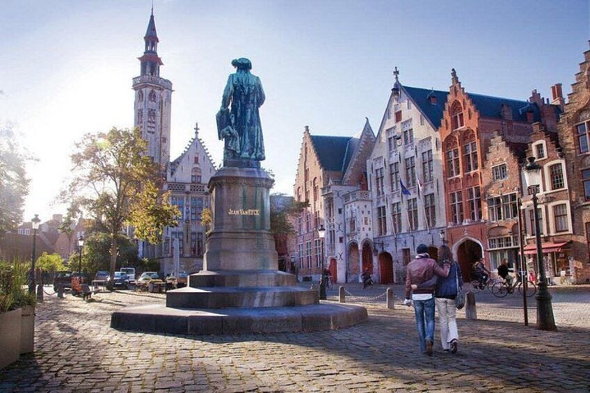 A cobblestone square with a statue, historic buildings, and a tower in the background. 4