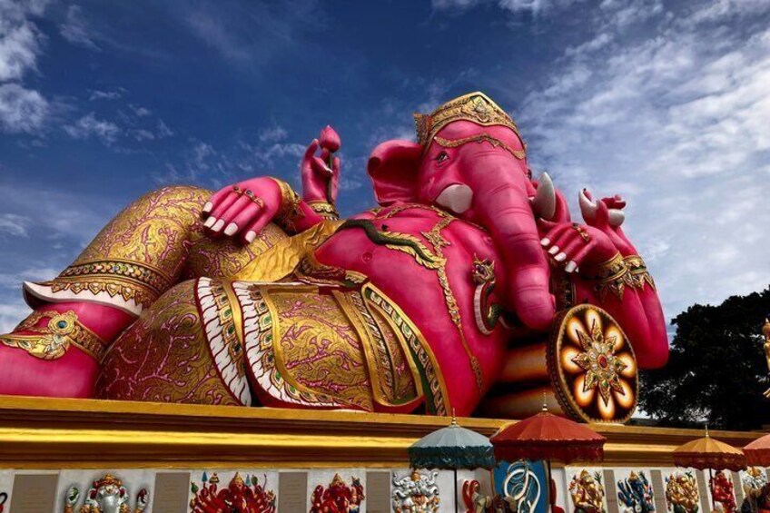 A large pink elephant statue with gold accents and a golden wheel. 1